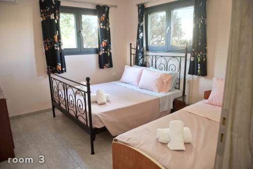 two twin beds in a room with two windows at ELENA'S VILLA WITH VIEW in Néa Tríglia
