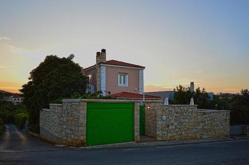 a green garage in front of a brick wall at Villa Ithaca in Varípetron