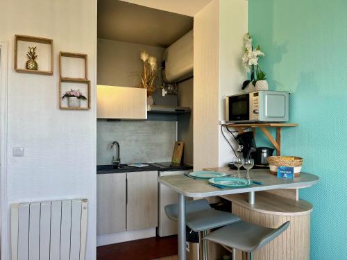 una pequeña cocina con mesa y microondas en La Vague, en Calais