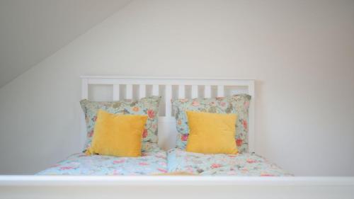 a white bed with two yellow pillows on it at Land-Apartments Netphen in Netphen