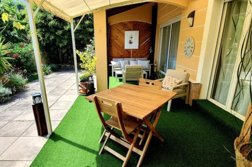 un patio con mesa y sillas en el césped en Les Jardins - 4 pers - 10 min Plage - Mandelieu, en Mandelieu-la-Napoule