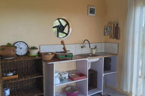 Zimmer mit einer Theke mit einem Waschbecken und einer Uhr in der Unterkunft Kichuguu farmstay cottage in Mtito Andei