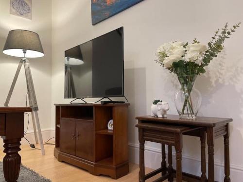 a living room with a tv and a table with a vase of flowers at 3 Bedroom Home In Stoke in Stoke on Trent