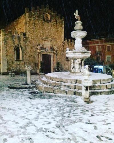 a fountain in front of a building in the snow at Appartamento Georgiana in Taormina