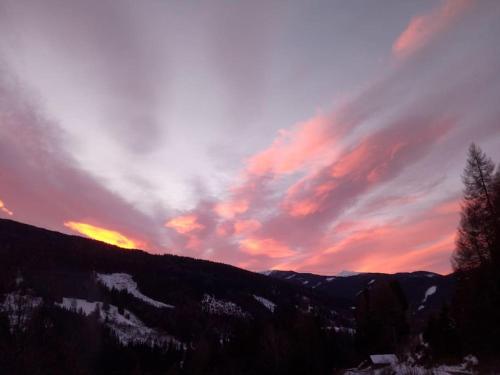 a sunset over a mountain with snow and clouds at FW Schnuckel in 300a Altem Bergbauernhaus 1110m in Plessnitz