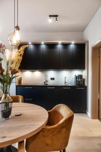 a kitchen with a wooden table and black cabinets at Residenz Illyrica Tirol in Westendorf