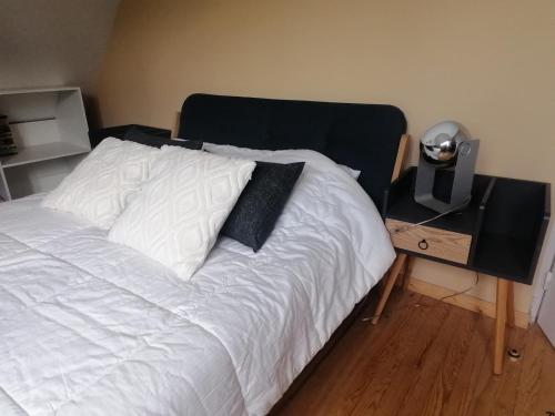 sypialnia z białym łóżkiem z czarnym zagłówkiem w obiekcie VILLA DES HETRES w mieście Saint-Nectaire