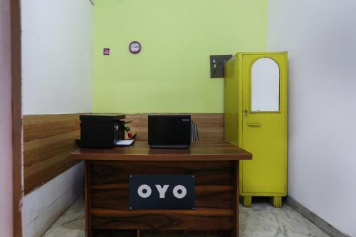 un escritorio con un letrero en él junto a una puerta verde en OYO Anand Villa en Nueva Delhi