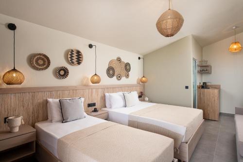 2 bedden in een hotelkamer met witte lakens bij Castaway Suites - Studios Christos in Limenaria
