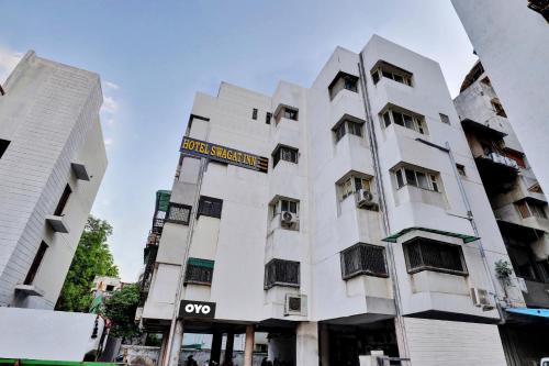 un edificio blanco con un cartel. en OYO Flagship Hotel Swagat Inn, en Ahmedabad