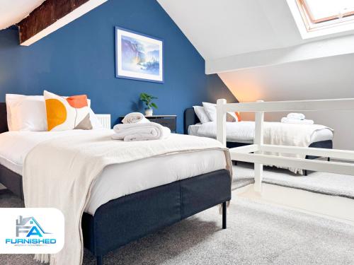 a bedroom with two beds and a blue wall at Modern House - Great Location - Free Parking in Headingley