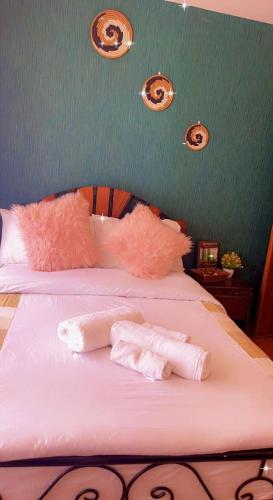 - un lit avec des oreillers roses et 2 serviettes dans l'établissement Cyton by Alma, à Muchatha