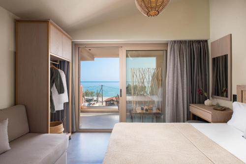 een slaapkamer met een bed en uitzicht op de oceaan bij Castaway Suites - Studios Christos in Limenaria
