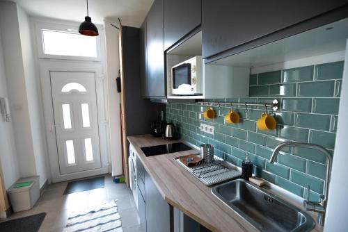 eine Küche mit einem Waschbecken, einem Fenster und einer Tür in der Unterkunft Classy Creation Apartment in Budapest
