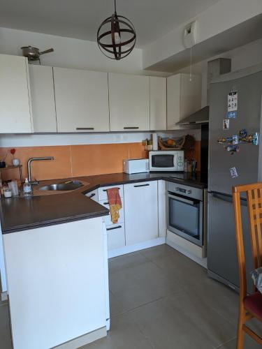 La cuisine est équipée de placards blancs, d'un évier et d'appareils électroménagers. dans l'établissement Maison 3 pièces avec jardin - 5 min des plages, à La Ciotat