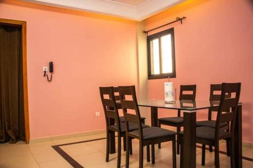a dining room with a table and chairs and a window at Résidence l'appart in Yaoundé