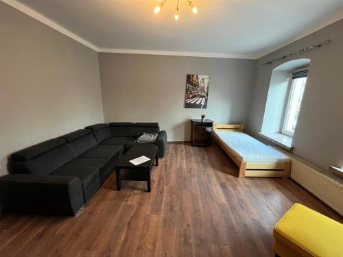 ein Wohnzimmer mit einem schwarzen Sofa und einem Bett in der Unterkunft ul. Mała 18/2 in Częstochowa