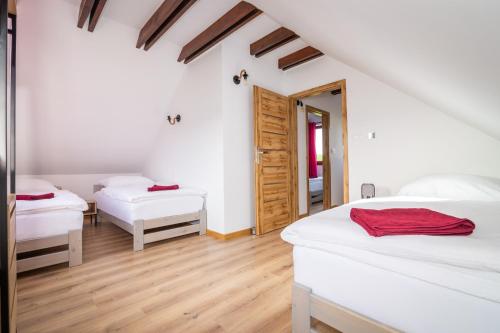 two beds in a room with white walls and wooden floors at Dolinowo in Kudowa-Zdrój