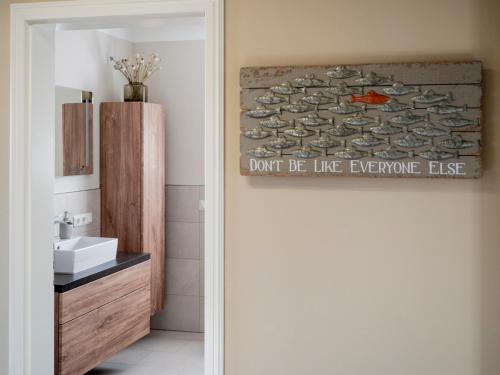 ein Badezimmer mit Waschbecken und ein Schild, auf dem steht, dass nicht wie alle anderen sein soll in der Unterkunft Haus Ostseezwilling 2 in Zingst
