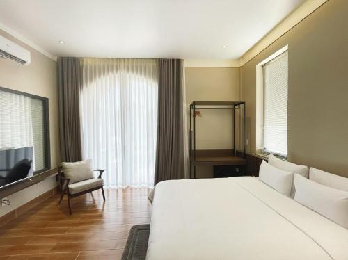 a bedroom with a large white bed and a chair at MELA HOTEL in Mỹ Thạch