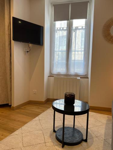 Il comprend un salon doté d'une table et d'une télévision à écran plat. dans l'établissement Le Cocon Studio Auxerre Centre, à Auxerre