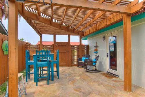 Un patio con pérgola de madera y mesas y sillas azules. en Lorna Beach Cottage at Spanish Village, en Port Aransas