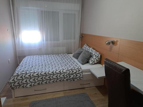 een bed in een kleine kamer met een raam bij Apartman Marger in Niš