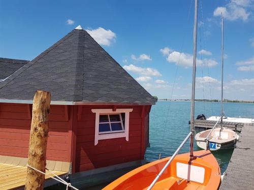 una pequeña casa roja en un muelle con un barco en Maritime Freizeit Camp "MFC" Erfurter Seen en Stotternheim
