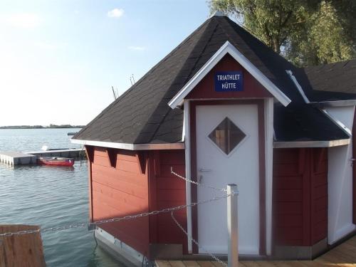 uma casa de barco vermelha e branca na água em Maritime Freizeit Camp "MFC" Erfurter Seen em Stotternheim