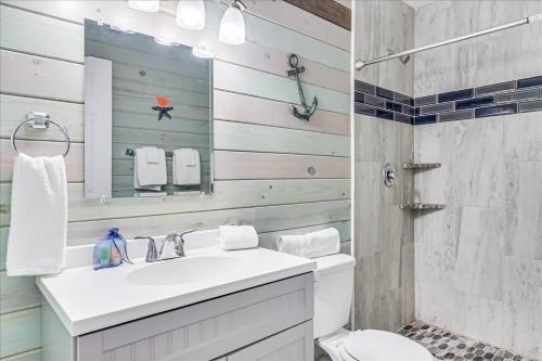 a bathroom with a sink and a toilet and a mirror at Blue Marlin Cottage (Anchor Courts #3) in Port Aransas