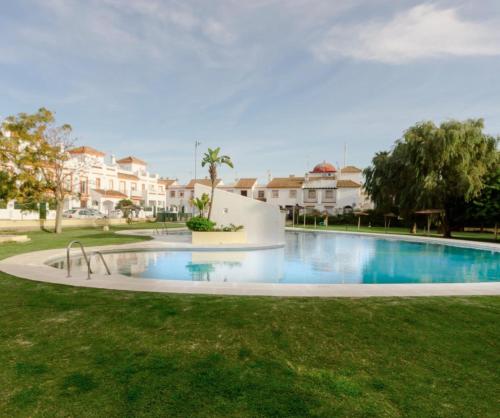 a large swimming pool in a yard with houses at APARTAMENTO APARTACLUB REFORMADO in Chiclana de la Frontera