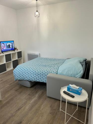 a bedroom with a bed and a table with a remote control at superbe studio meublé avec parking in Maubeuge