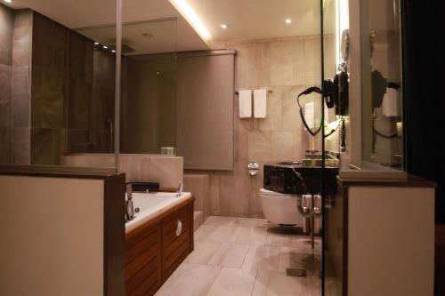 a bathroom with a tub and a toilet and a sink at Monarch Hotel Amman in Amman