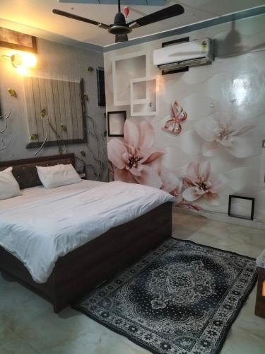 govind resort في نويدا الكبرى: غرفة نوم مع سرير مع زهور على الحائط