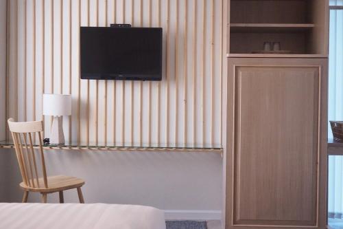 1 dormitorio con TV en la pared y silla en Shanti-Retreat Hotel, en Pua