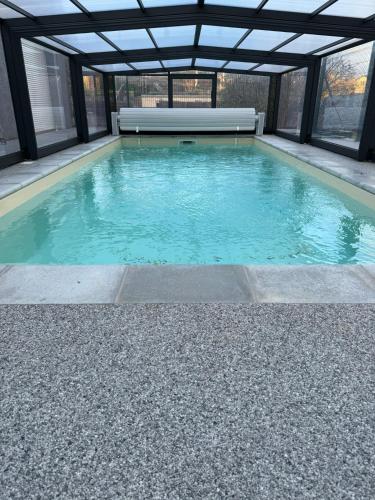 - une piscine avec un plafond en verre et de l'eau bleue dans l'établissement Villa avec piscine à Mende capacité 12 personnes, à Mende