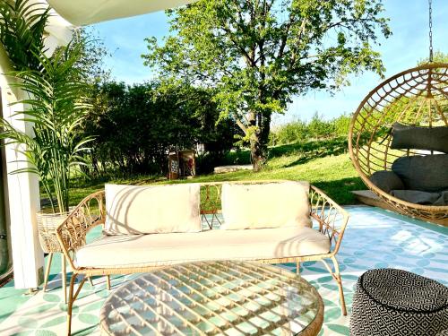 a rattan couch on a patio with a swing at Bohemian Eco Lodge at lake Balaton in Kisapáti