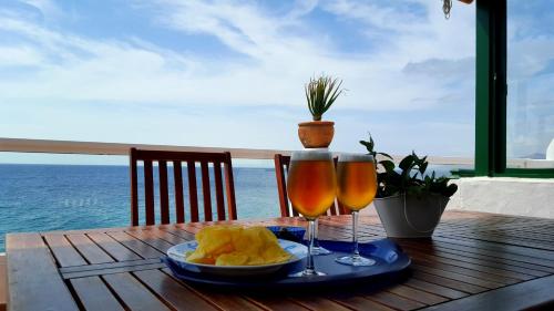 stół z dwoma kieliszkami do wina i talerzem jedzenia w obiekcie Casa Tito w Puerto del Carmen