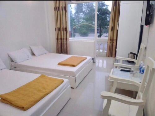 a white living room with two beds and a chair at Khách sạn Đại Huệ in Dong Quan