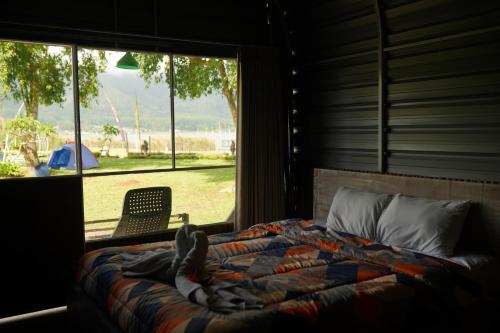 a bedroom with a bed and a window and a chair at Bali Strawberry Glamping and Camp Bedugul in Tabanan
