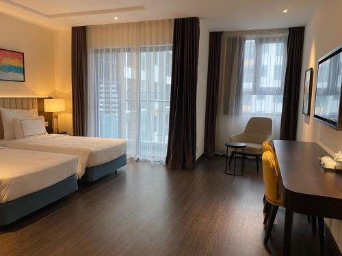 een hotelkamer met een bed, een bureau en een raam bij The Sapphire Ha Long in Ha Long