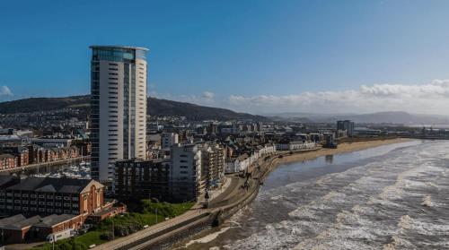 a city with a tall building next to a river at Captivating 1-Bed Apartment in Swansea in Swansea