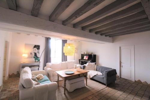 una sala de estar con muebles blancos y techo de madera. en Jallanges, en Fontevraud-l'Abbaye