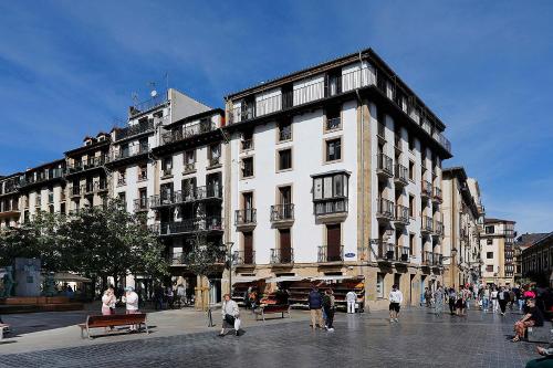 un gran edificio blanco con gente caminando delante de él en Pensión Balerdi Autocheck-in, en San Sebastián
