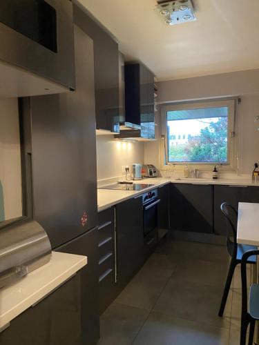 une cuisine avec des armoires noires et une fenêtre dans l'établissement Confortable 3 pièces 75m2, Vincennes Centre, à Vincennes
