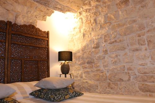 a bedroom with a bed with a stone wall at Le Badesse Mitrate by il pumo di puglia in Conversano
