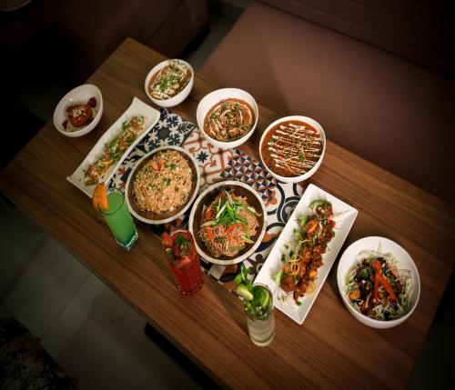 a table with many bowls of food on it at Hotel The Avoir Asansol in Āsansol