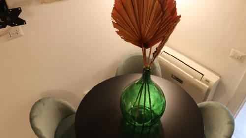 a green vase on a table with a flower in it at Le Badesse Mitrate by il pumo di puglia in Conversano