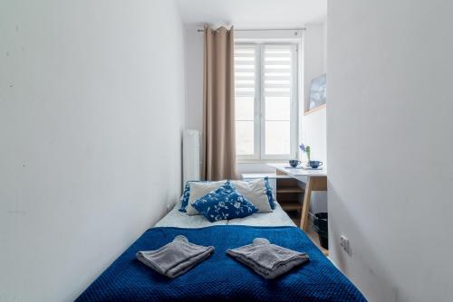 Un dormitorio con una cama azul con dos almohadas. en Szeroka Royal Rooms, en Gdansk