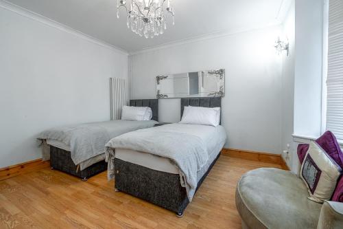 a bedroom with two beds and a chandelier at Spacious Worcester City Centre House in Worcester